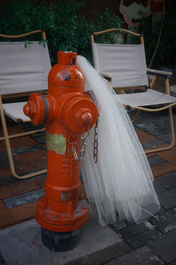 A red fire hydrant draped with a white veil